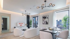 Een moderne woonkamer met een eethoek, een televisie en uitzicht over de stad.