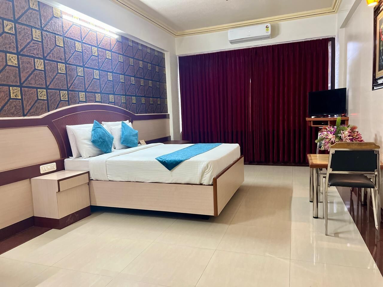 A hotel room with a bed, bedside table, and a desk with a chair.
