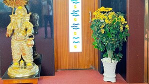 A reception area with a wooden door labeled "BANQUET HALL," a statue, and a potted plant with yellow flowers. - The Grand Krishna Rooms (Bengaluru)