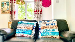 A leather sofa with two decorative pillows featuring ocean-themed designs and text. - 2 Bedrooms Cornish Holidays For Penzance & St Ives (Penzance)