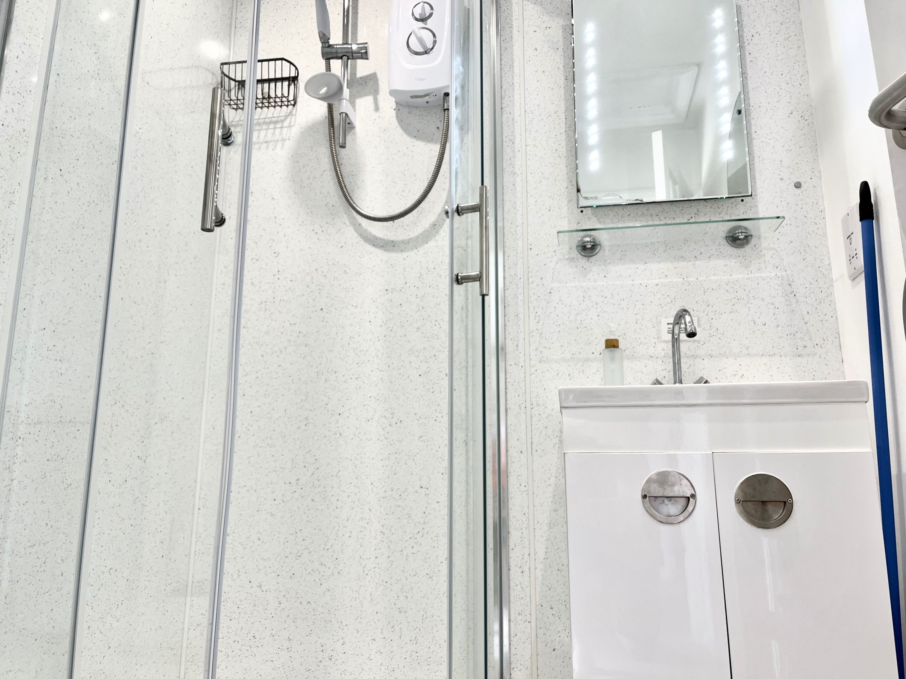 A bathroom with a shower, a sink, a mirror, and a toilet.
