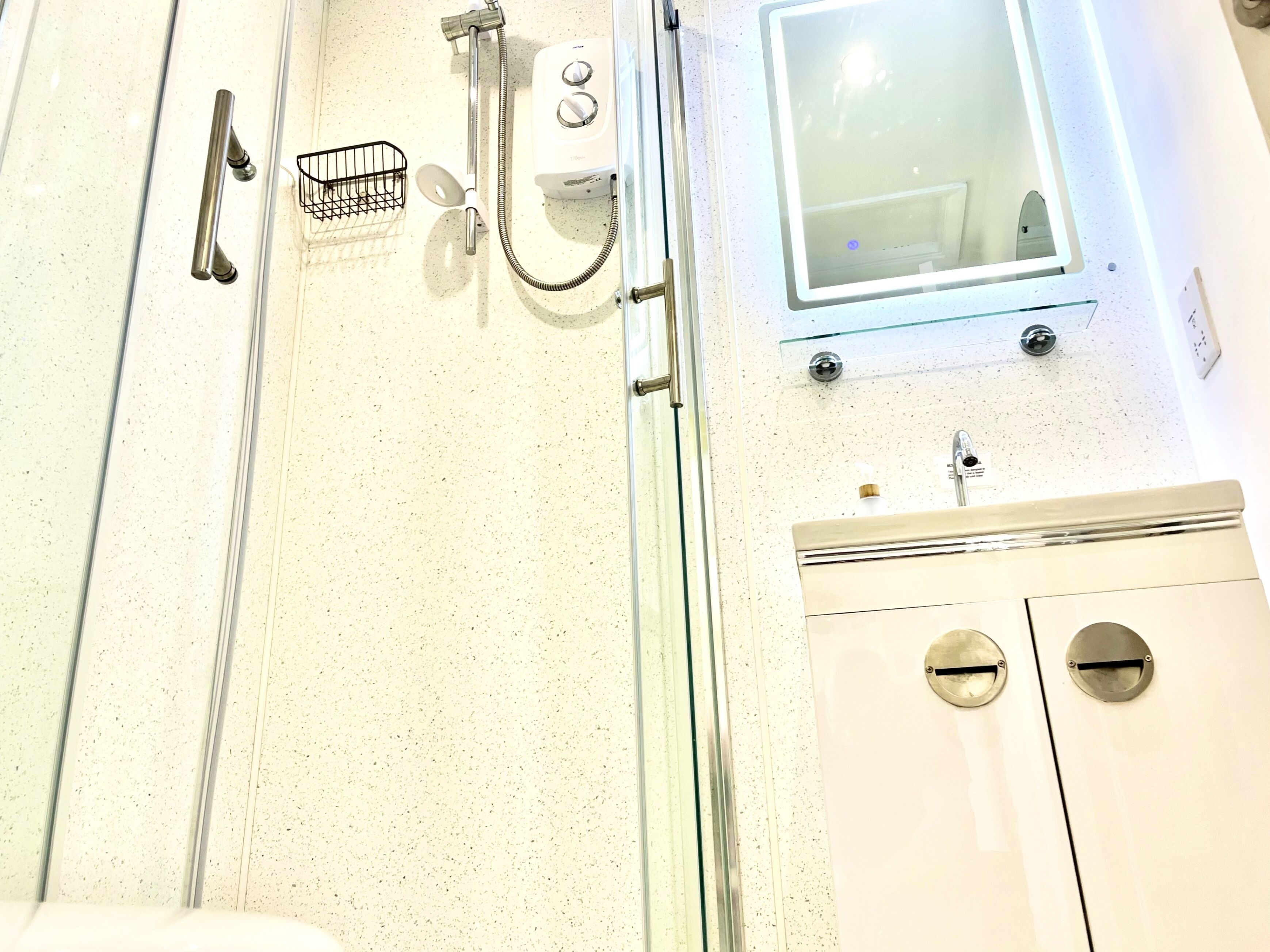 Une salle de bain équipée d’une douche, d’un miroir, d’un lavabo et de toilettes.
