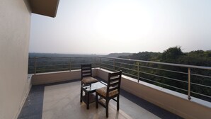 A balcony with two chairs and a table, overlooking a forested landscape. - Ocean View The Apartment Hotel (Consua)