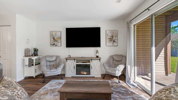 Ein Wohnzimmer mit Kamin, zwei Sesseln, einem Couchtisch und einem an der Wand befestigten Fernseher.