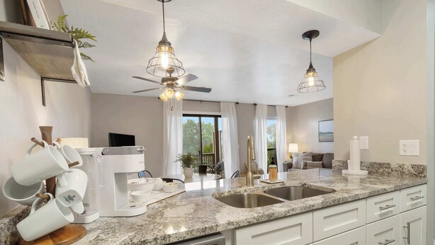 A modern kitchen with granite countertops, stainless steel appliances, and pendant lighting. - Troon Golf View | Golf Course View | On-site Amenities (Branson)
