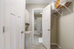 A narrow hallway with a shower area, a drying rack, and a white door. - Troon Golf View | Golf Course View | On-site Amenities (Branson)