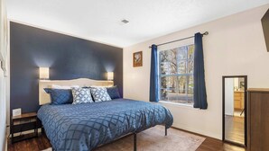 A bedroom with a bed, bedside tables, a window with curtains, and a view of the outside. - The Nautical Nook – Charming Walk-In Condo for 4! (Branson)