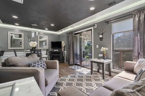 Un salon moderne avec une cheminée, des canapés, un téléviseur et un balcon agrémenté de rideaux.