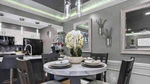 Una cocina moderna con armarios blancos, un refrigerador negro y una zona de comedor con una mesa redonda y sillas.