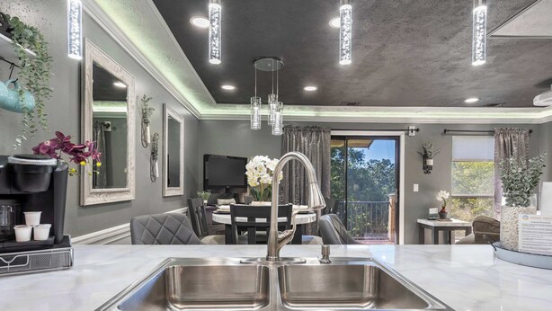 Una cocina moderna con un lavamanos grande de acero inoxidable, luces colgantes y un comedor con una mesa redonda y sillas.