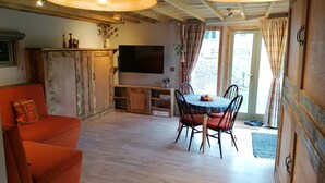 Un salon confortable avec un canapé, une table à manger et des chaises, un téléviseur et un meuble en bois.
