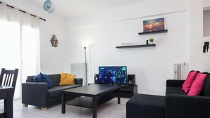Una sala de estar moderna con un televisor de pantalla plana, dos sofás, una mesa de centro y un comedor con una silla y una mesa.
