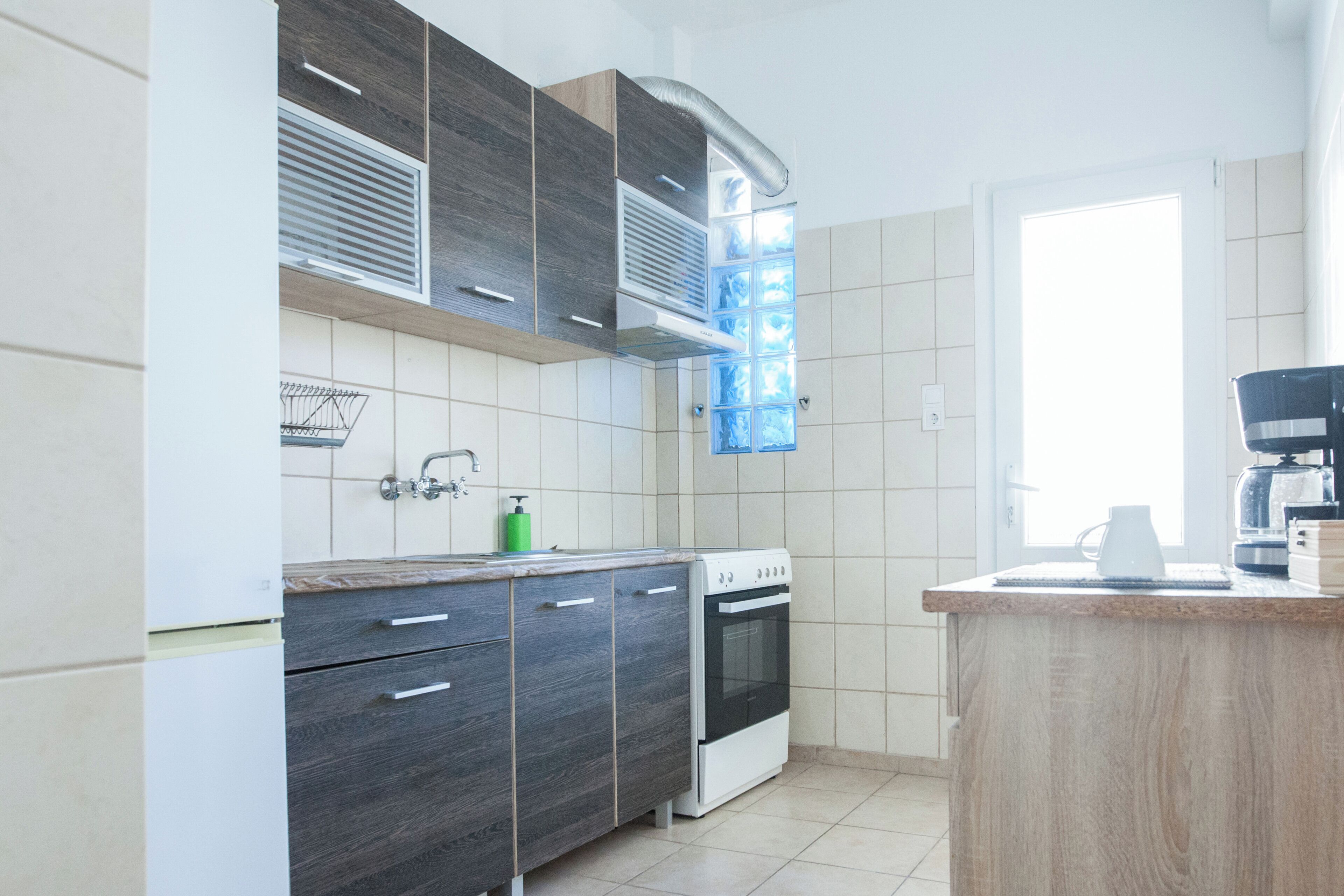 A modern kitchen with dark wood cabinets, a white stove, and a window providing natural light.