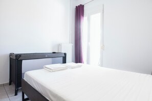 A neatly made bed with white linens, a black headboard, and a small table with a white lamp beside it. - Stylish 1 Bd Apt w Balcony in Petralona (Athens)
