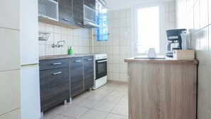Una cocina moderna con armarios de madera oscura, una estufa blanca y un ventanal con persianas.