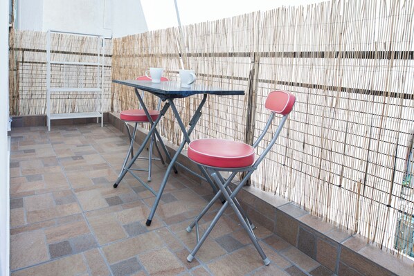 An outdoor patio with a table and two chairs, a bamboo fence, and a tiled floor. - Stylish 1 Bd Apt w Balcony in Petralona (Athens)