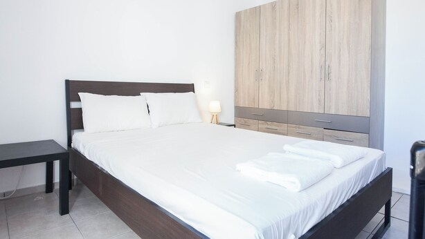 Un dormitorio moderno con una cama grande, una mesita de noche, un armario y una lámpara.