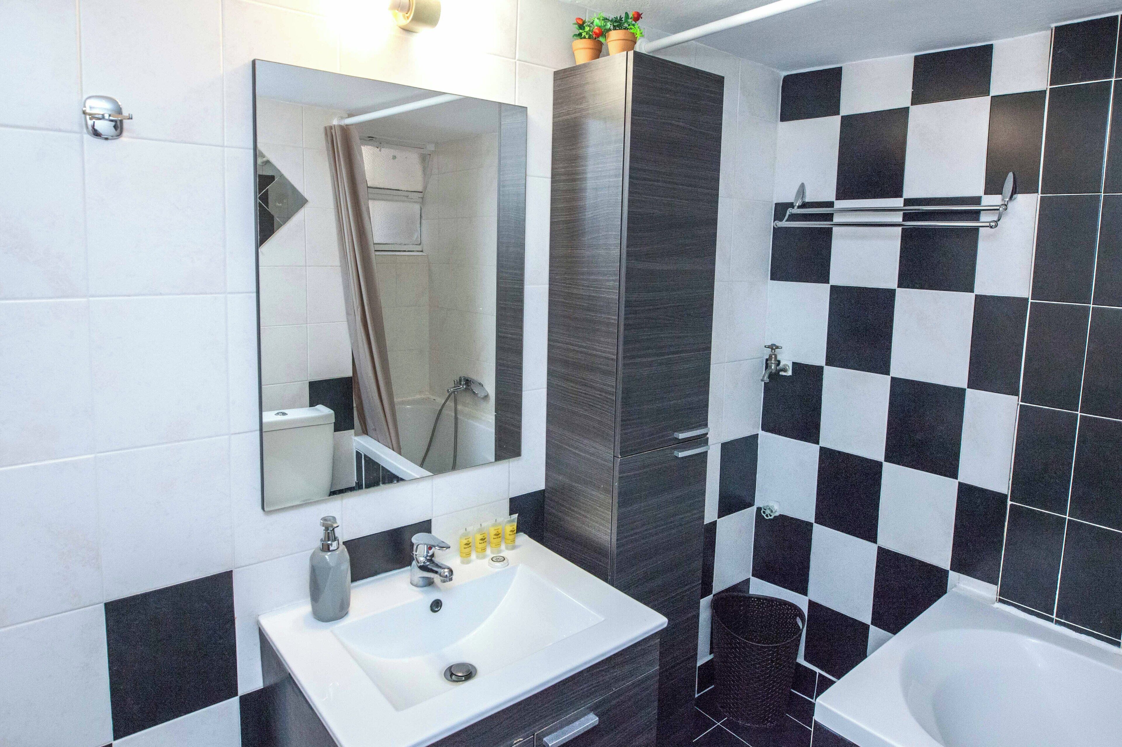 A modern bathroom with a white sink, a mirror, a shower, and a bathtub.
