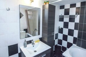 A modern bathroom with a white sink, a mirror, a shower, and a bathtub. - Stylish 1 Bd Apt w Balcony in Petralona (Athens)
