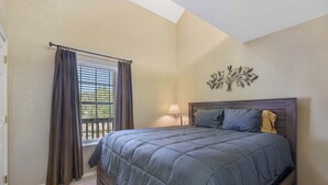 Een slaapkamer met een groot bed, een raam met gordijnen, een wandlamp en een decoratief kunstwerk.