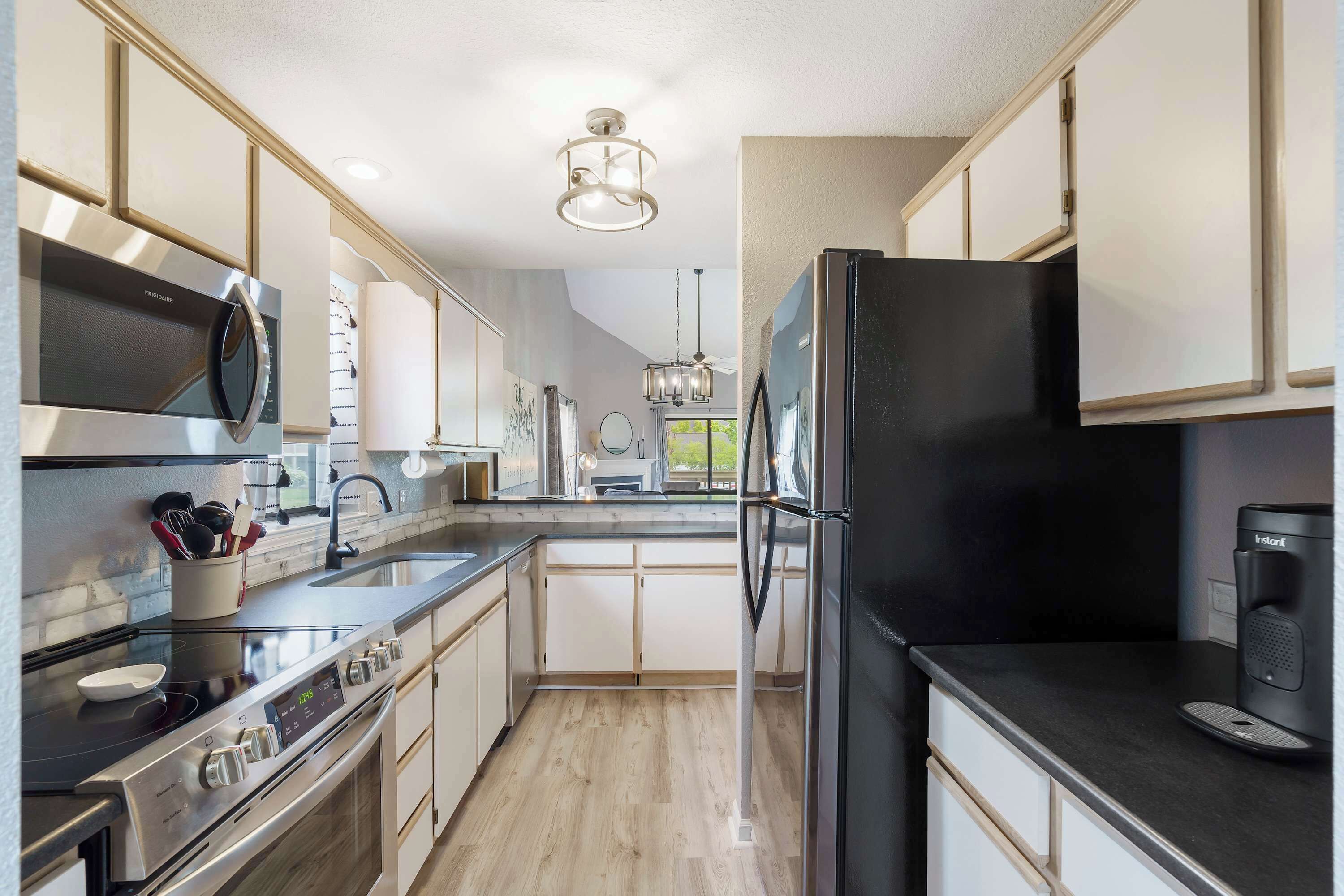 A modern kitchen with stainless steel appliances, a black refrigerator, and a coffee maker.
