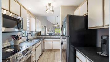 A modern kitchen with stainless steel appliances, a black refrigerator, and a coffee maker.