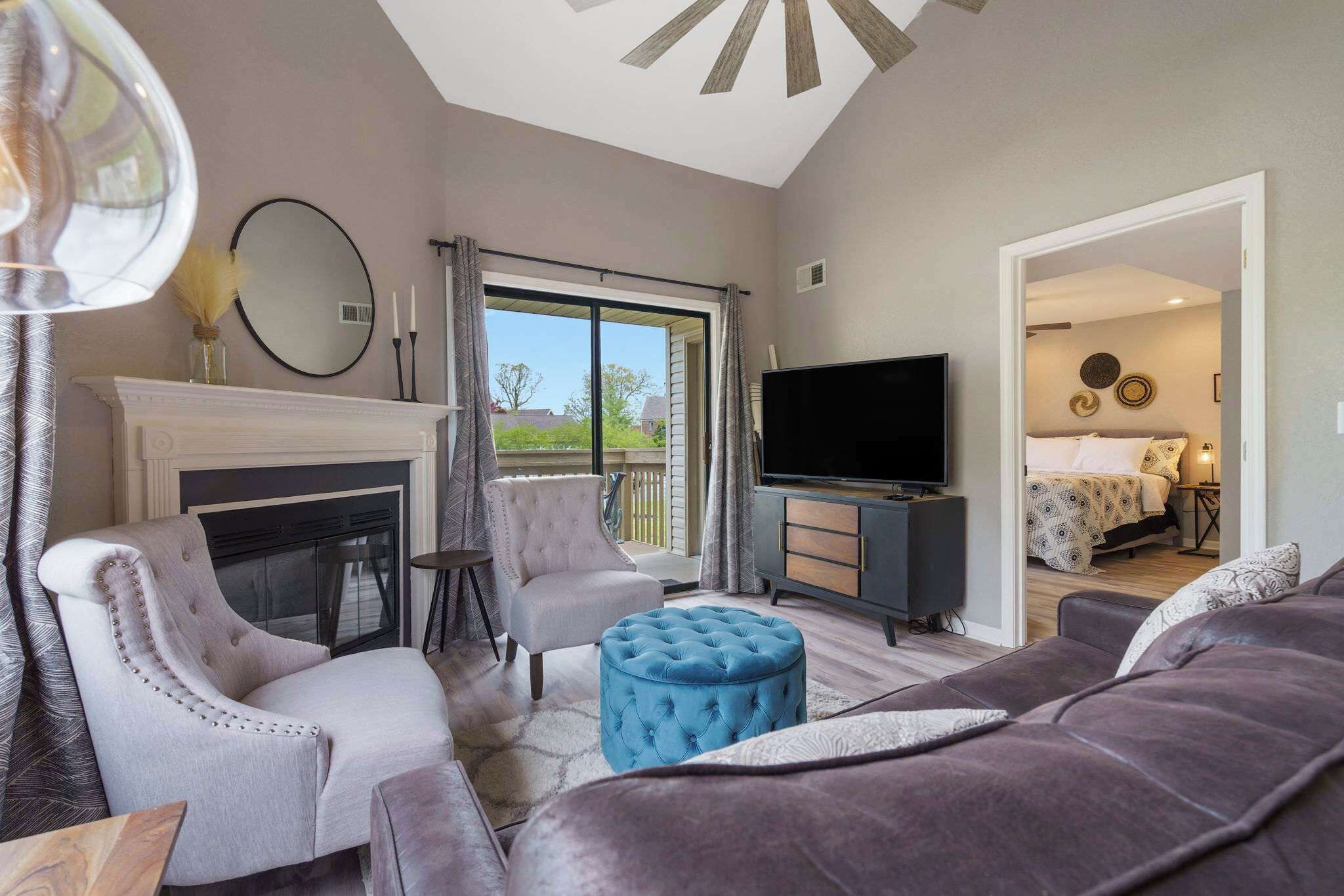 A modern living room with a fireplace, a television, and a balcony with a view.