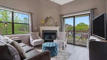 A spacious living room with a fireplace, large windows, and a sliding glass door leading to an outdoor area.