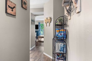 A hallway with artwork, a welcome sign, and a shelf with board games.