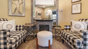 A cozy living room with two checkered sofas, a round ottoman, a fireplace, and framed artwork on the walls. - Fairview Escape | Holiday Hills Branson | Golf | Outdoor Pools (Branson)