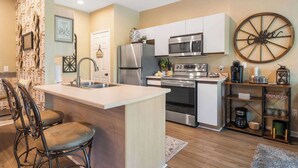 A modern kitchen with a central island, stainless steel appliances, and a decorative wheel on the wall. - Fairview Escape | Holiday Hills Branson | Golf | Outdoor Pools (Branson)