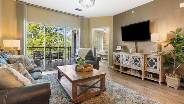 A spacious living room with a large window, a wooden coffee table, a sofa, a TV, and a cabinet. - Fairview Escape | Holiday Hills Branson | Golf | Outdoor Pools (Branson)