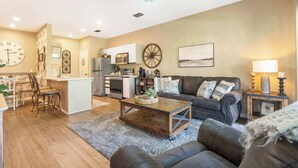 A modern living room with a sofa, coffee table, and a dining area with chairs and a table. - Fairview Escape | Holiday Hills Branson | Golf | Outdoor Pools (Branson)