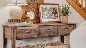 A wooden desk with a lamp, framed picture, books, and a potted plant.