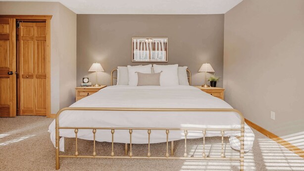 A bedroom with a bed, wooden wardrobe, bedside lamps, and a ceiling fan.