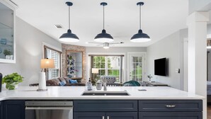 A modern kitchen with a large island, dark cabinetry, and pendant lighting. - Brookside Duo | Peaceful Views! (Branson)