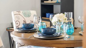 A dining table set with blue bowls, plates, and glasses, accompanied by a vase of white flowers.