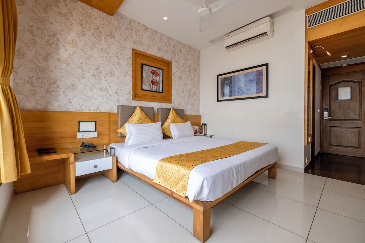 A neatly arranged hotel room with a bed, bedside tables, a desk, and a door.