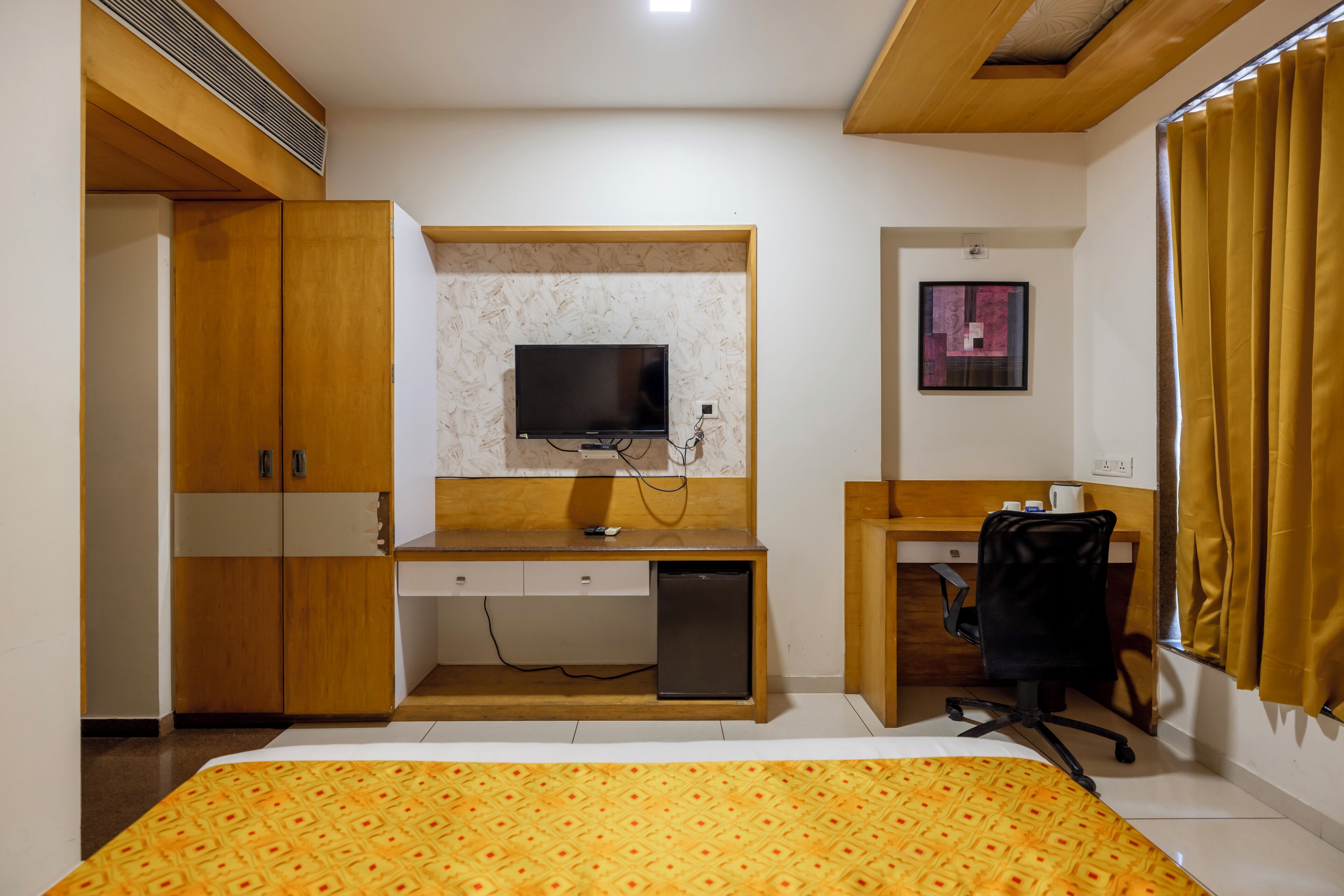 Een slaapkamer met een bed, een bureau, een stoel, een televisie en een kledingkast.