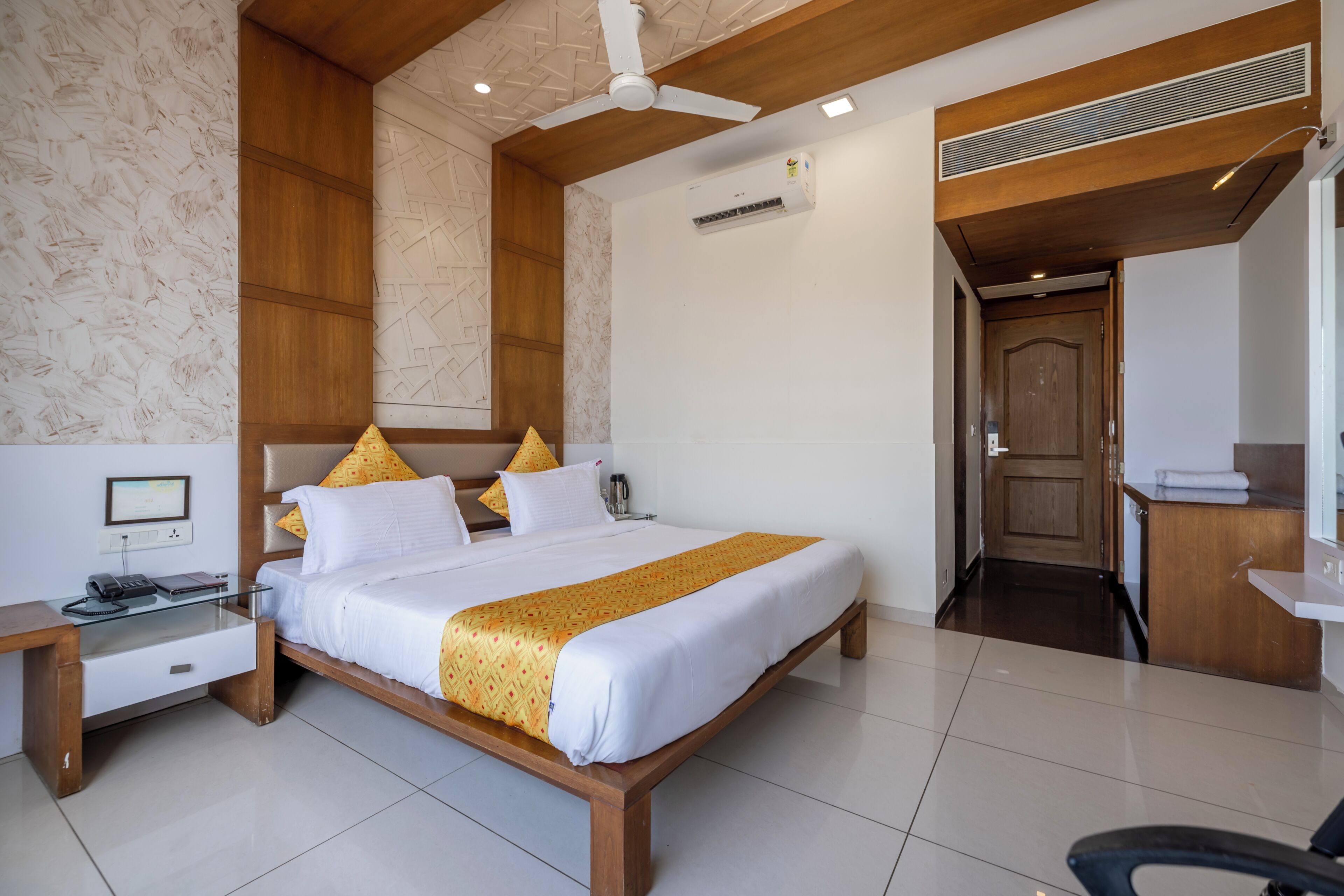 Une chambre d’hôtel comprenant un lit, une table de chevet, un bureau, une chaise et une porte donnant accès à une salle de bain.