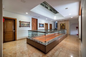 A modern hotel lobby with a glass display table, wooden doors, and artwork on the walls. - Manek the Ocean View (Dwarka)