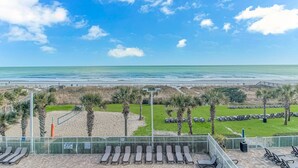 A beach view with a fenced area, palm trees, and lounge chairs. - 🌞Ocean View | Indoor Heated Water Park + Lazy River | Dunes Village Resort 338 (Myrtle Beach)