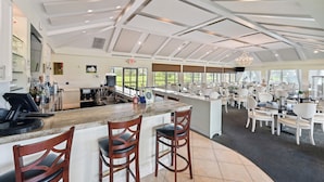 A spacious bar area with a high ceiling, ample seating, and a view of the outdoors. - 3 Mi to Downtown Naples: Country Club Condo! (Naples)