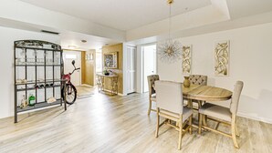 A spacious dining area with a wooden table and four chairs, a bicycle, and a decorative wall piece. - 3 Mi to Downtown Naples: Country Club Condo! (Naples)