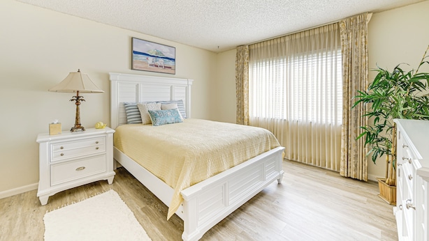 A bedroom with a bed, nightstand, lamp, and curtains. - 3 Mi to Downtown Naples: Country Club Condo! (Naples)