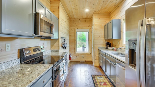 Una cocina moderna con encimeras de granito, electrodomésticos de acero inoxidable y paneles de madera.