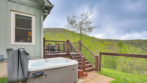 Un jacuzzi en una terraza de madera con vistas a una colina.