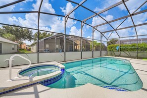 Una piscina con cerramiento de vidrio, rodeada por un deck blanco y un borde con azulejos azules.