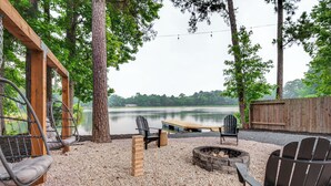 Järvenrantaterassi, jossa on Adirondack-tyyliset puutarhatuolit, nuotiopaikka ja puinen keinuteline.