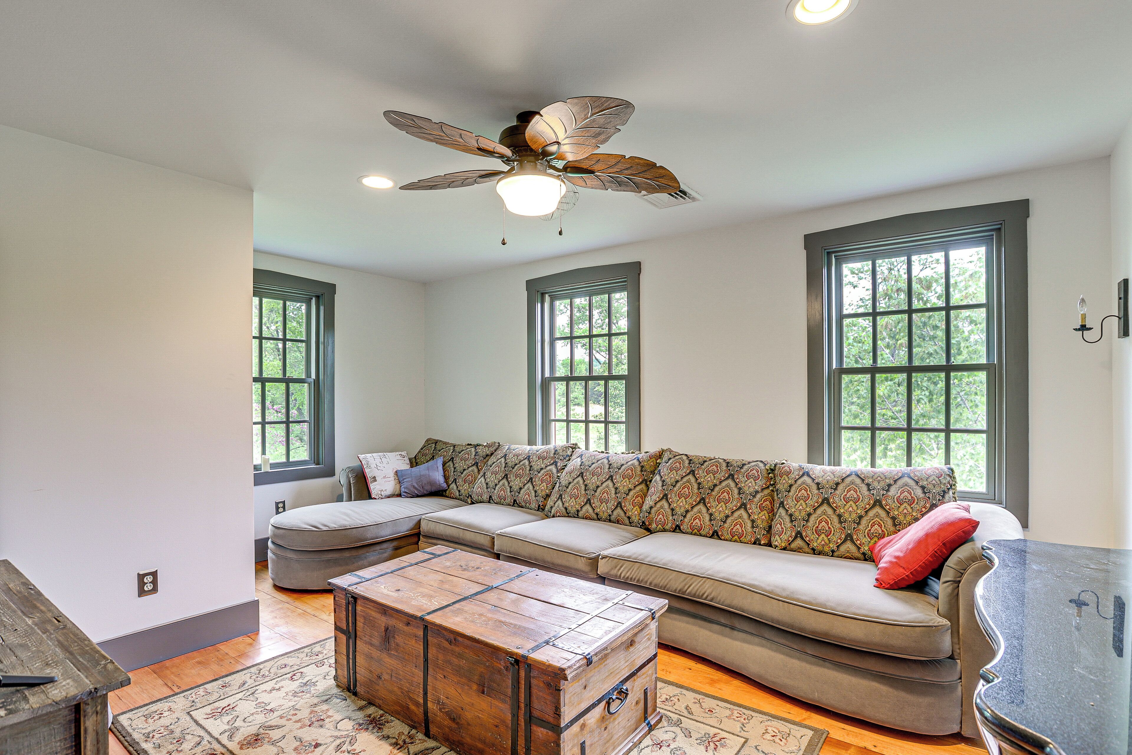 A spacious living room with a large sectional sofa, a wooden coffee table, and a ceiling fan.